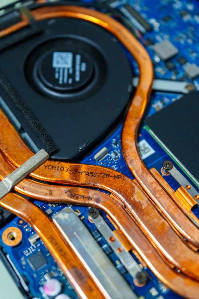 Detailed view of a laptops cooling system showing copper heat pipes and intricate circuitry.